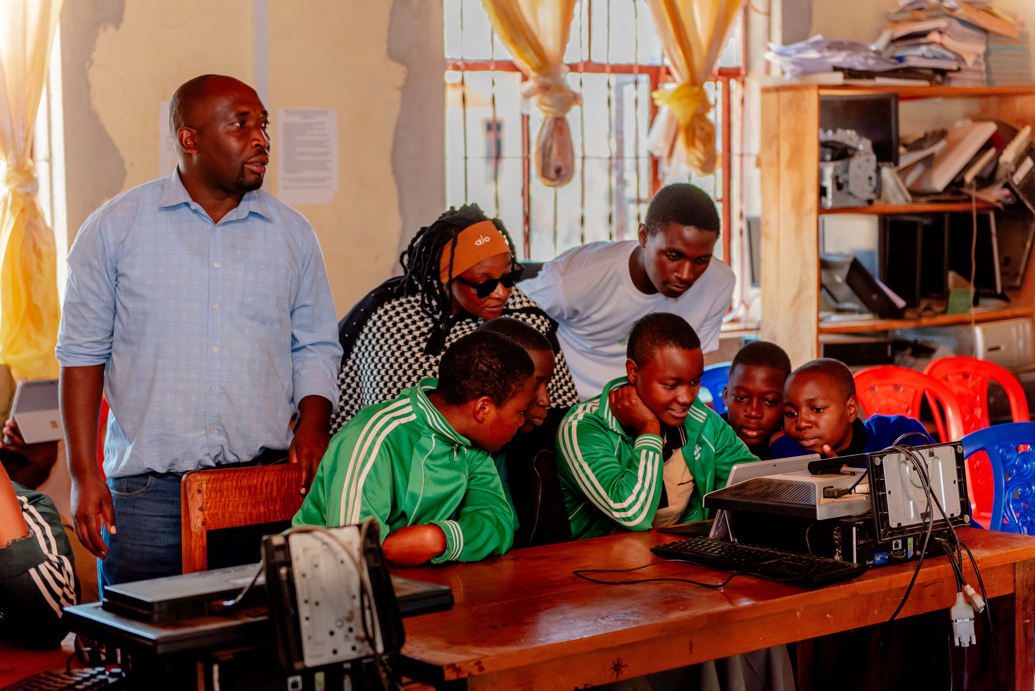 An adult standing beside students as they use the learning equipment